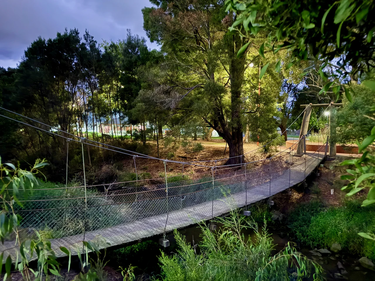 A suspension footbridge crosses the tree-lined creek.