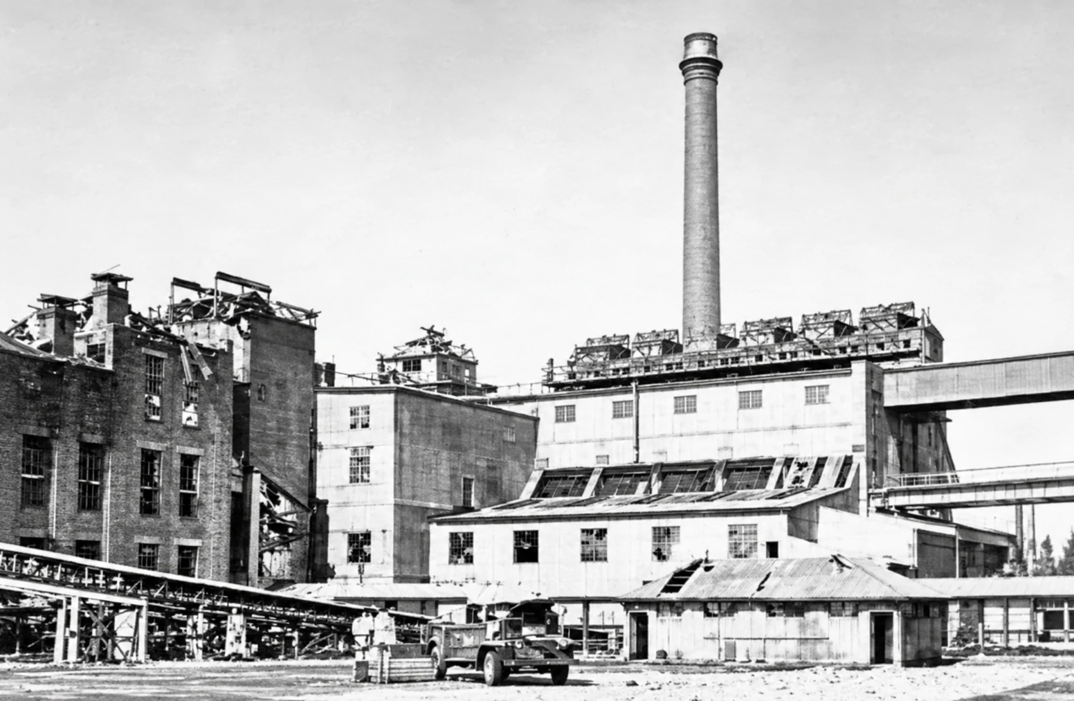 Black-and-white view of damaged buildings and roof structures at the Yallourn briquette factory after the March 1953 explosion.