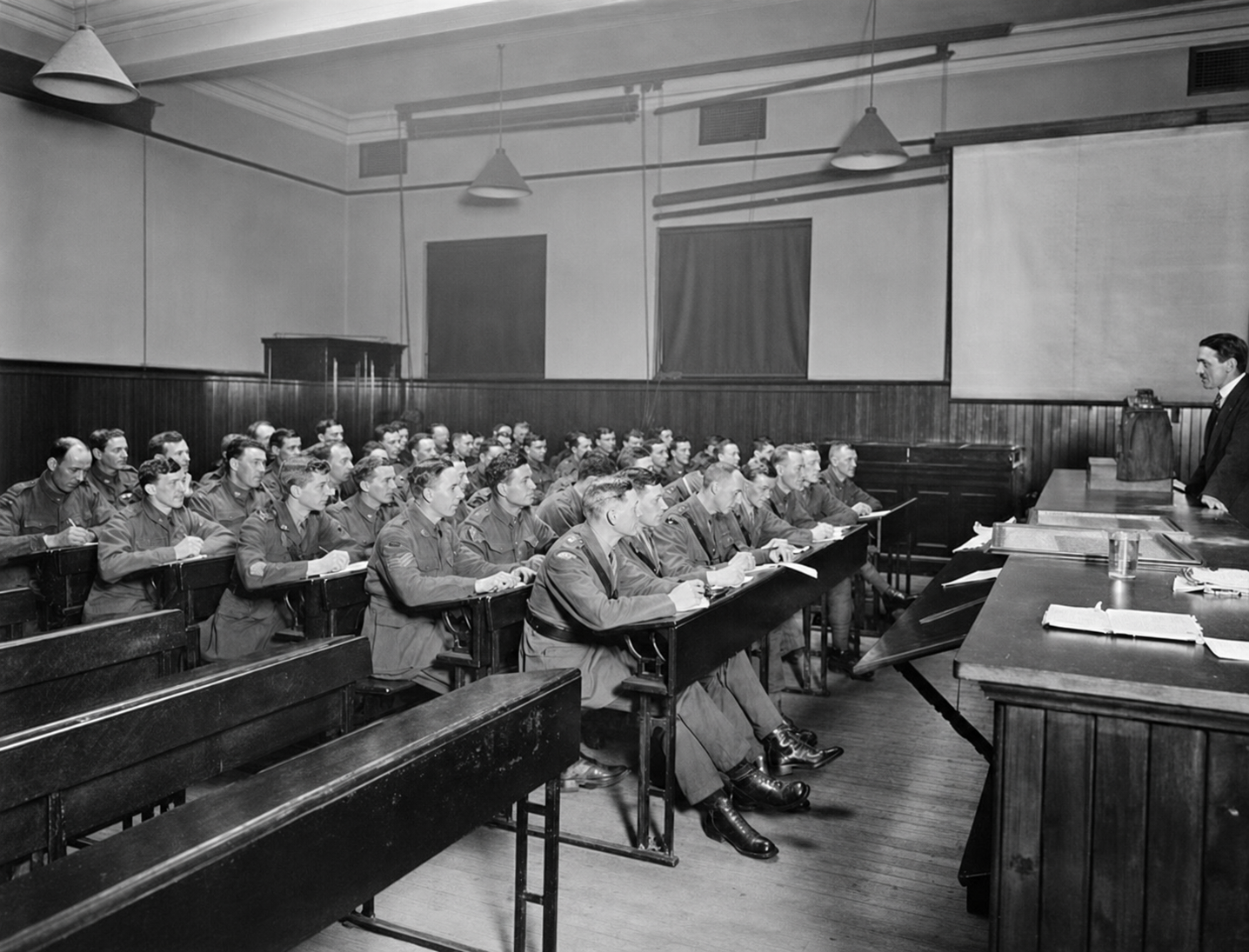 Australian servicemen in uniform sit at desks facing a lecturer in an Edinburgh University classroom.