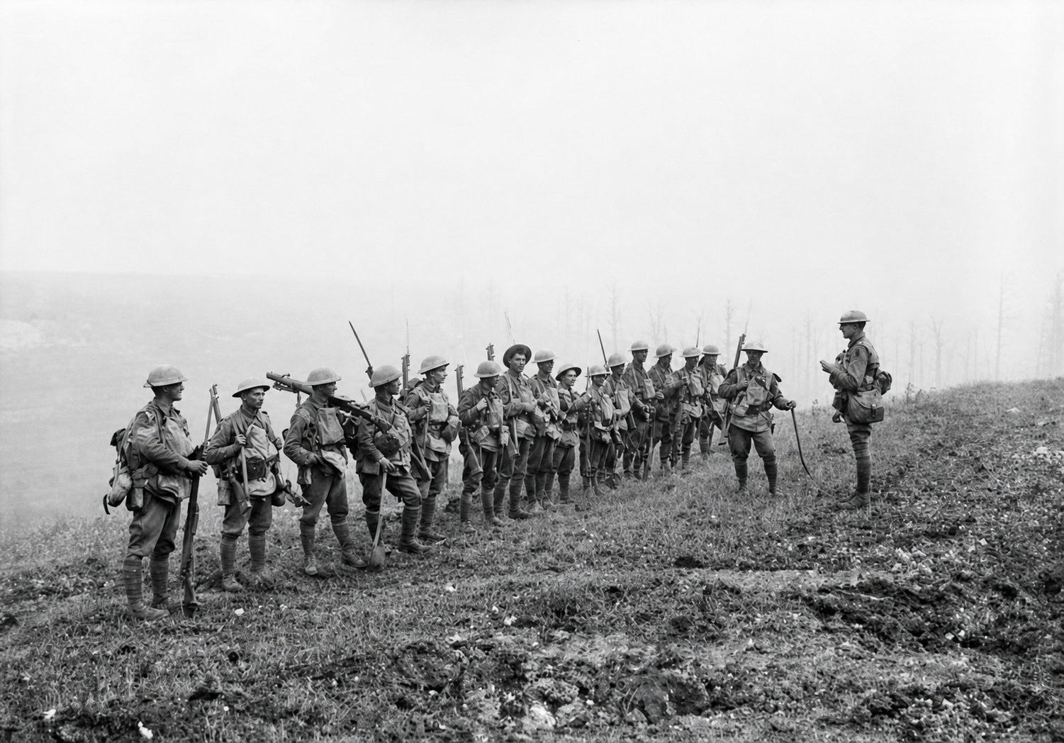 An officer stands before a long line of soldiers on open ground, with smoke obscuring the distance.
