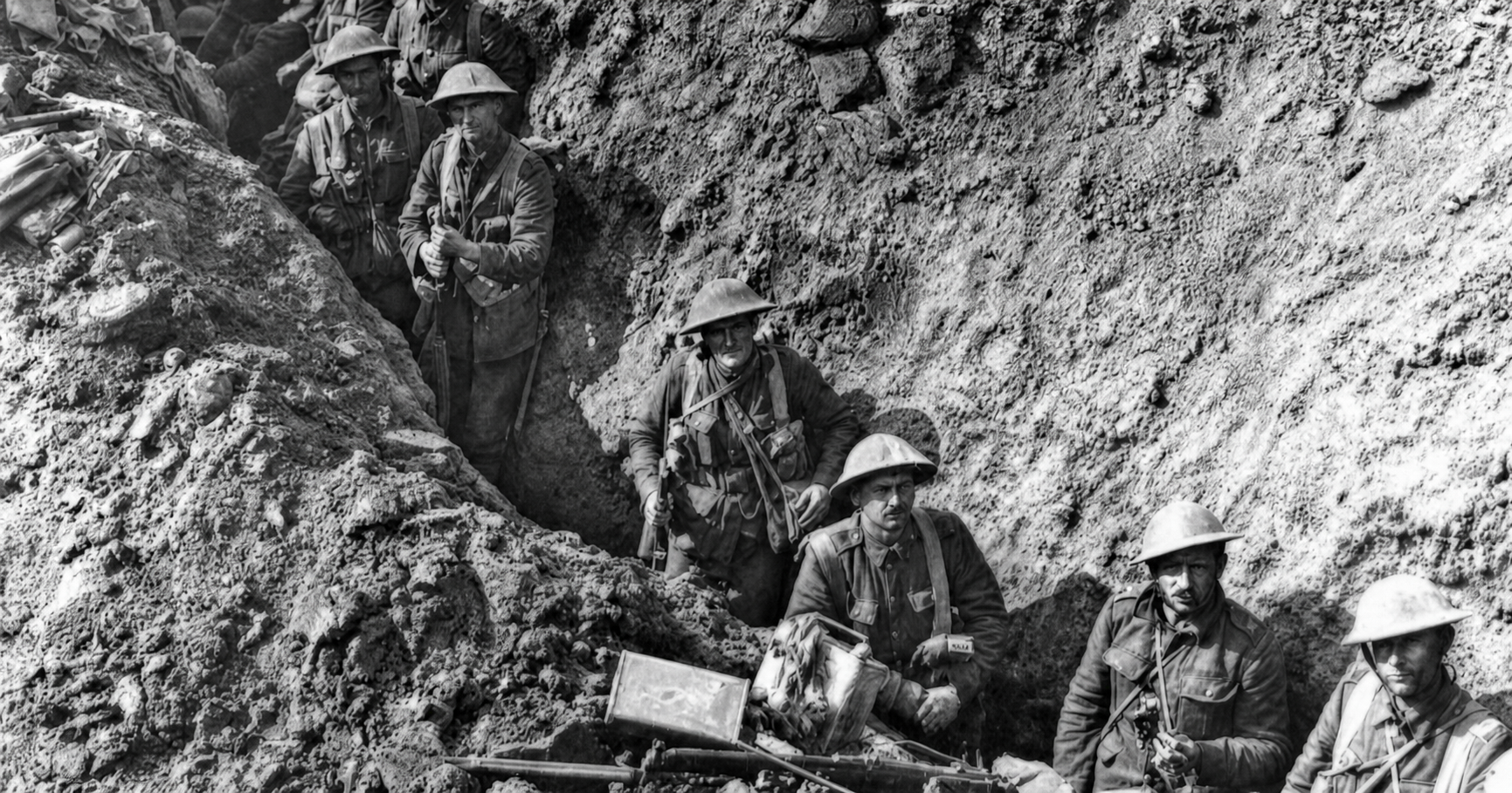Soldiers stand in a deep trench around a mounted machine gun and other equipment.