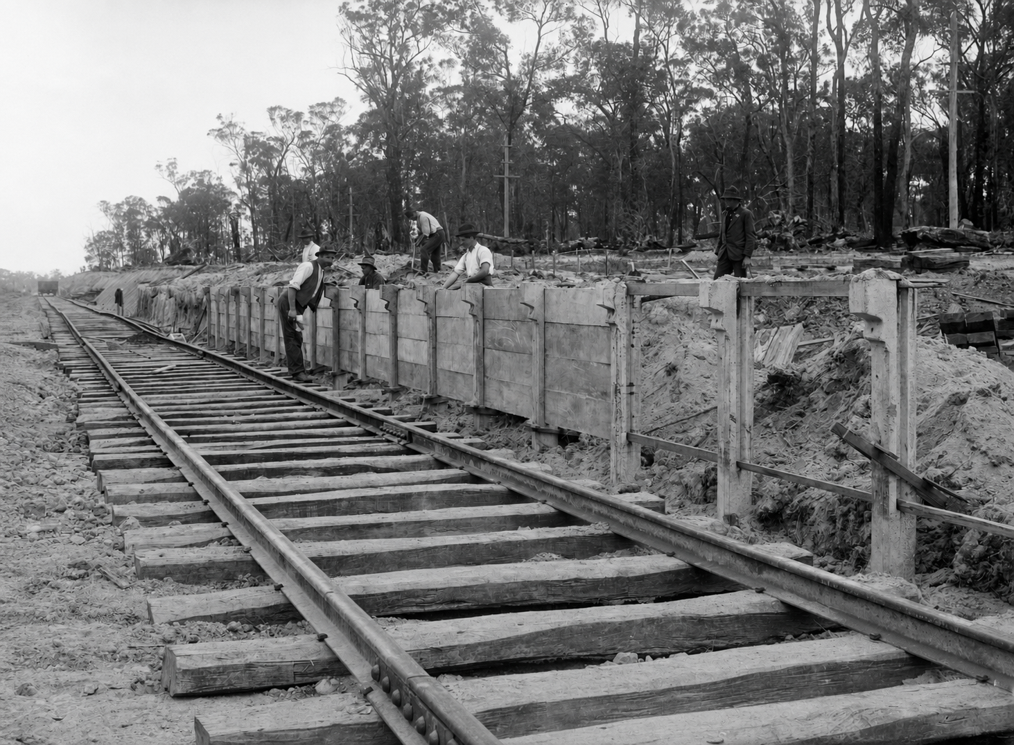Workers construct an elevated platform beside newly laid railway track at Yallourn, with sleepers and rails extending into the distance.
