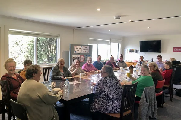 A group seated around a long table in a community room