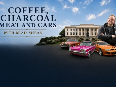 Three classic and custom cars — a red Jaguar, a pink 1950s American cruiser, and an orange Holden — parked in front of the Sir John Monash Museum at Yallourn.