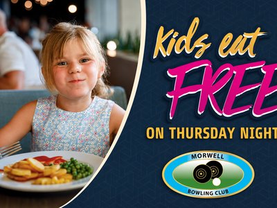 A smiling young girl sitting at a restaurant table with a plate of food, ready to enjoy a kids meal.