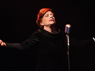 A performer on a grand stage bathed in warm spotlight, evoking the glamour of Carnegie Hall's legendary female singers.