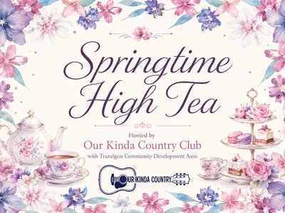 Elegantly set high tea table with tiered cake stands, floral arrangements, and fine china teacups in a community hall decorated for spring.