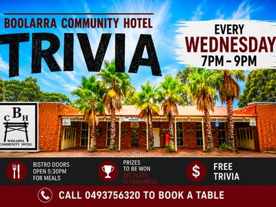 A lively pub trivia night at the Boolarra Community Hotel, with groups of smiling participants seated at long tables holding up answer sheets.