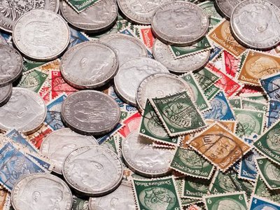 A display table covered in organised collections of postage stamps and coins at an indoor community fair.