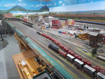 Close-up of detailed model trains on a scenic railway layout with realistic rockwork, trees and ballasted track.