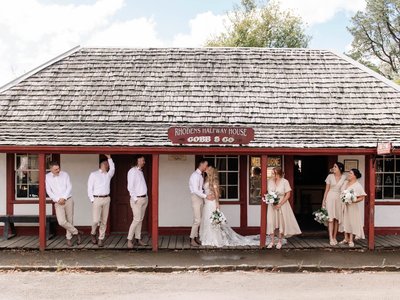 Couples and wedding vendors mingling among historic buildings and gardens at Old Gippstown Heritage Park in Moe.