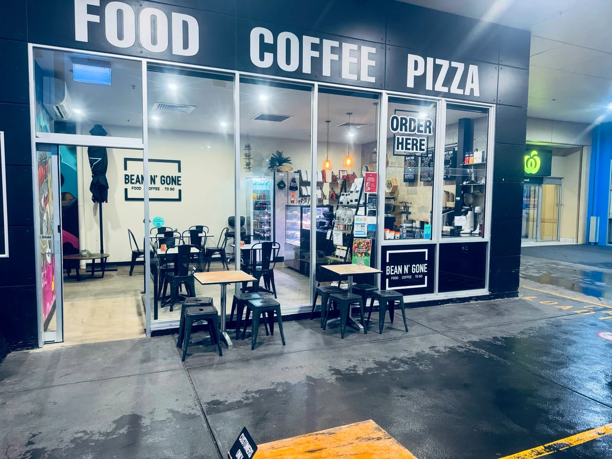 The glass-fronted Bean n' Gone café at Mid Valley, with indoor and outdoor tables and the service window beneath Food, Coffee and Pizza signs.