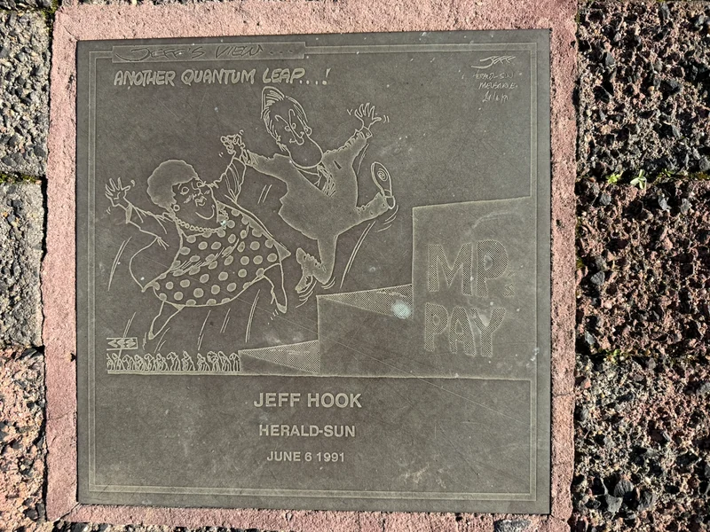 A cartoon artwork plaque set into the footpath in central Moe.