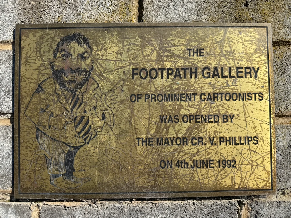 Original photograph of the weathered opening plaque for the Footpath Gallery of Prominent Cartoonists.