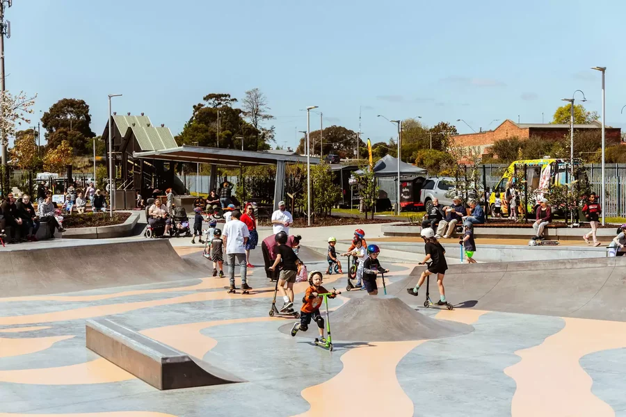 Children and adults moving through the concrete bowls and street zones of Moe Skatepark.