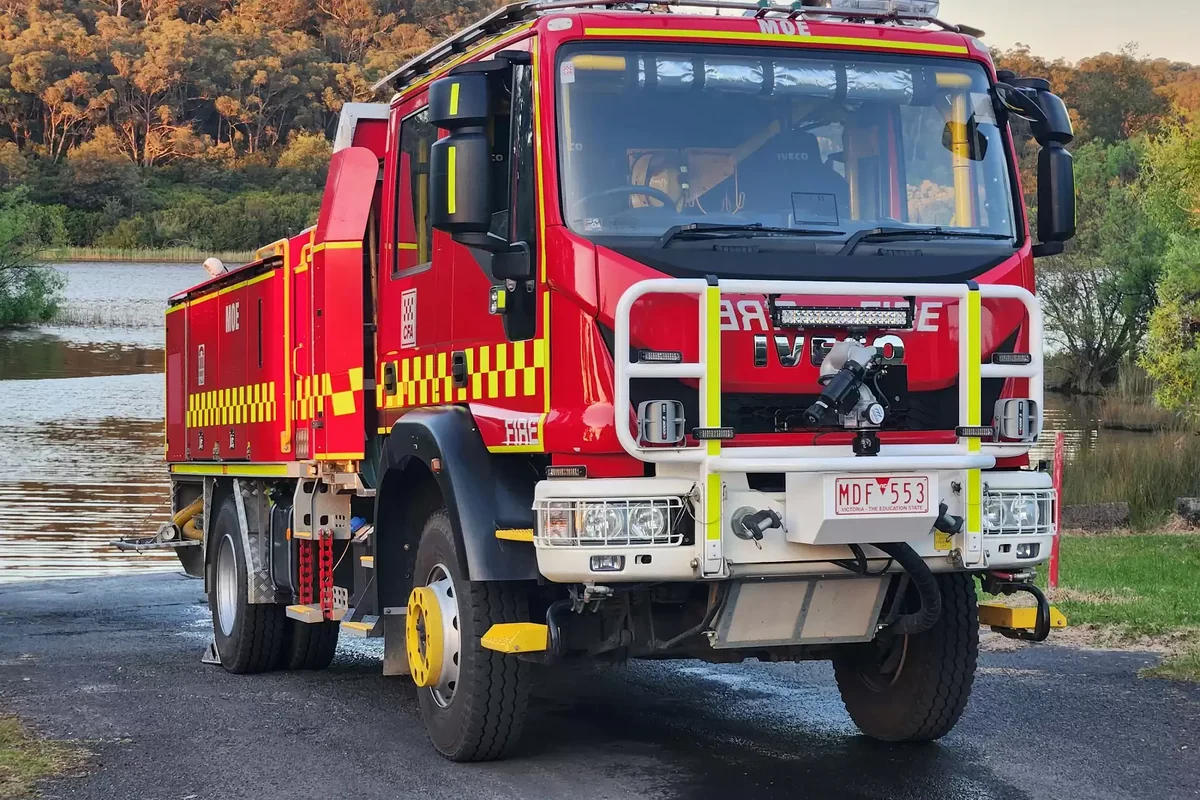 Firefighters stand beside a red CFA fire appliance inside Moe Fire Station.