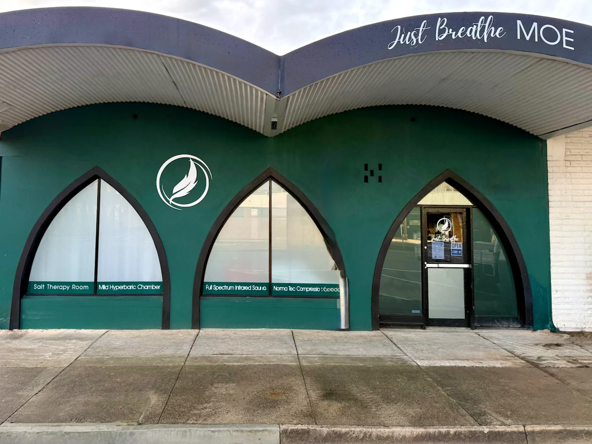 The green Just Breathe shopfront in Moe, with three pointed-arch windows beneath the Just Breathe Moe sign.