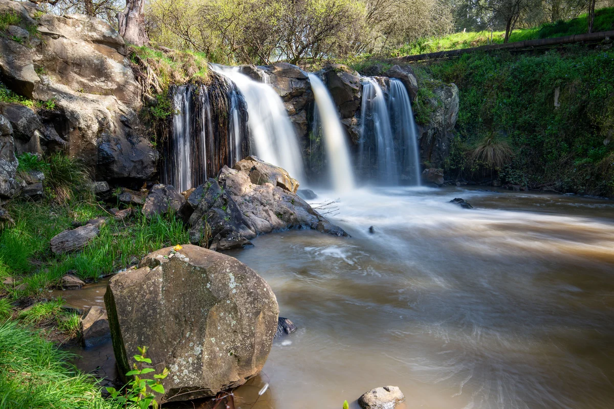Narracan Falls flowing in several channels over a broad rock shelf into the creek below.