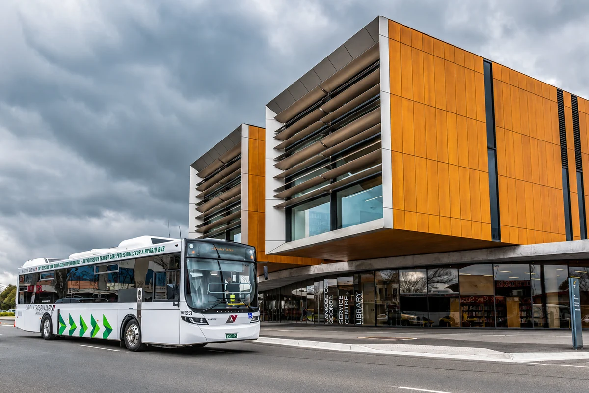A white and silver hybrid bus parked at the kerb outside Latrobe City’s library and service centre.