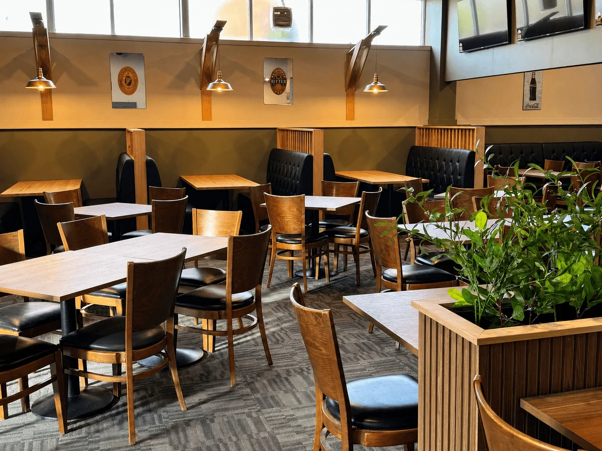 Tables, chairs and green plants in the Newborough Hotel dining room.
