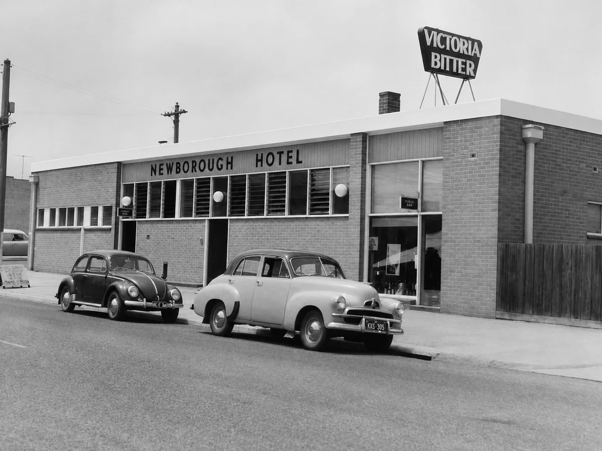 Historical black-and-white view of the Newborough Hotel with two cars parked outside.