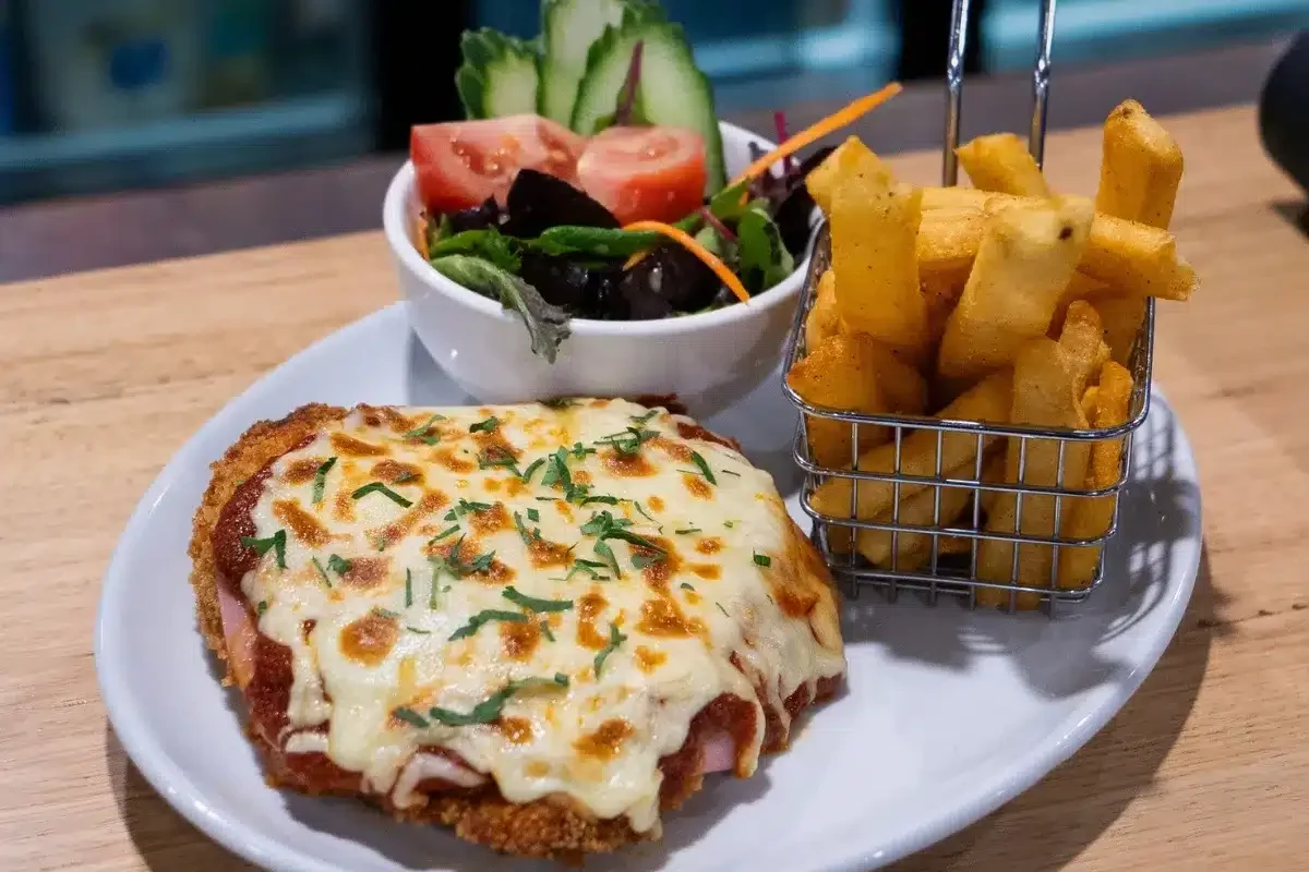 Chicken parma served with chips and a side salad at Newborough Hotel.