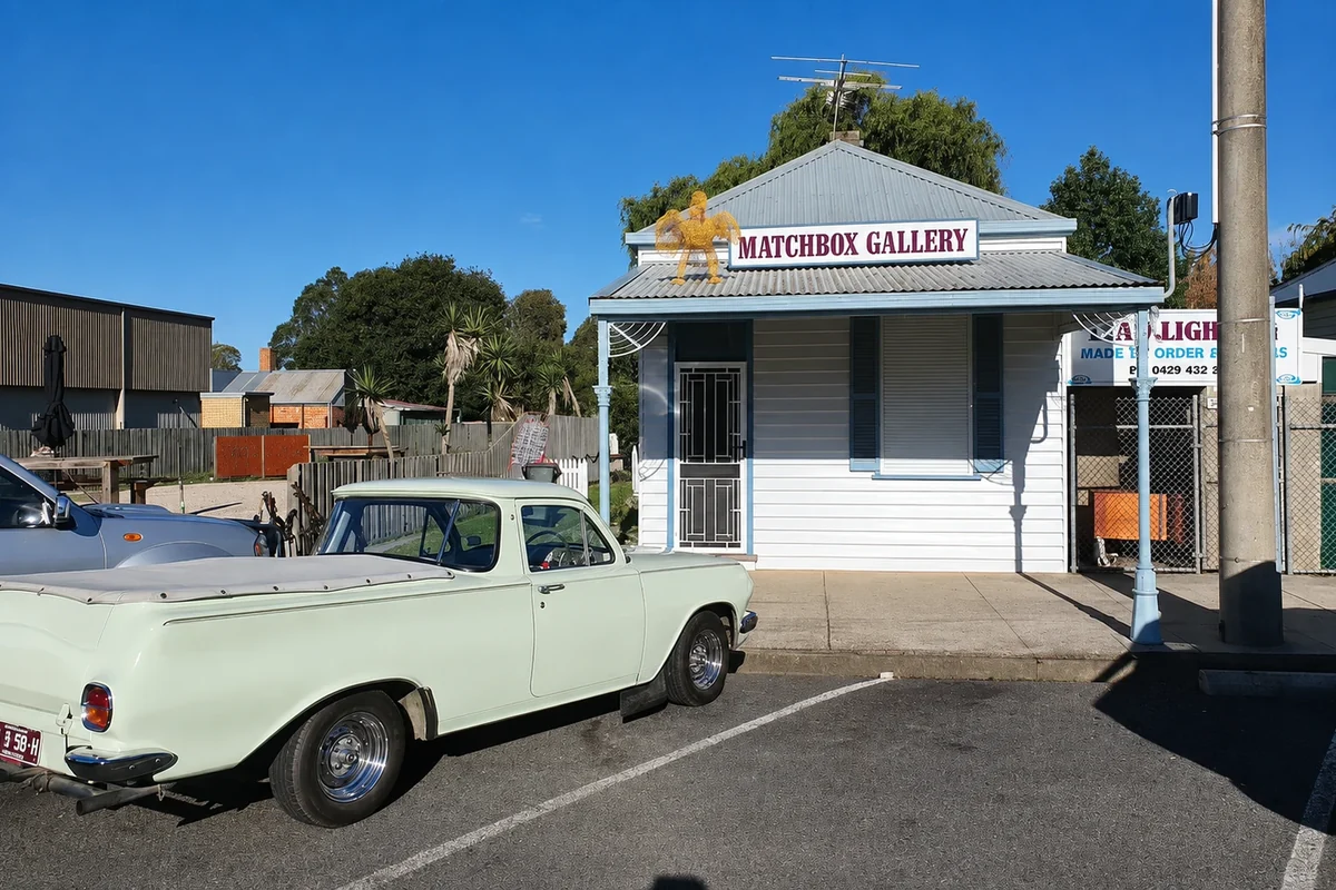 Matchbox Gallery's pale timber Main Street facade behind a parked vintage utility vehicle.