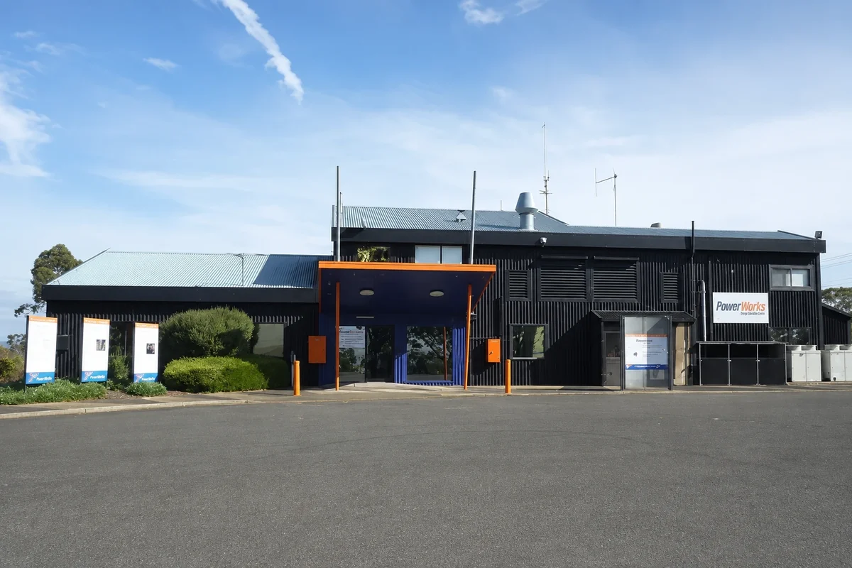 The dark-clad PowerWorks building with its orange entrance canopy viewed across the forecourt.