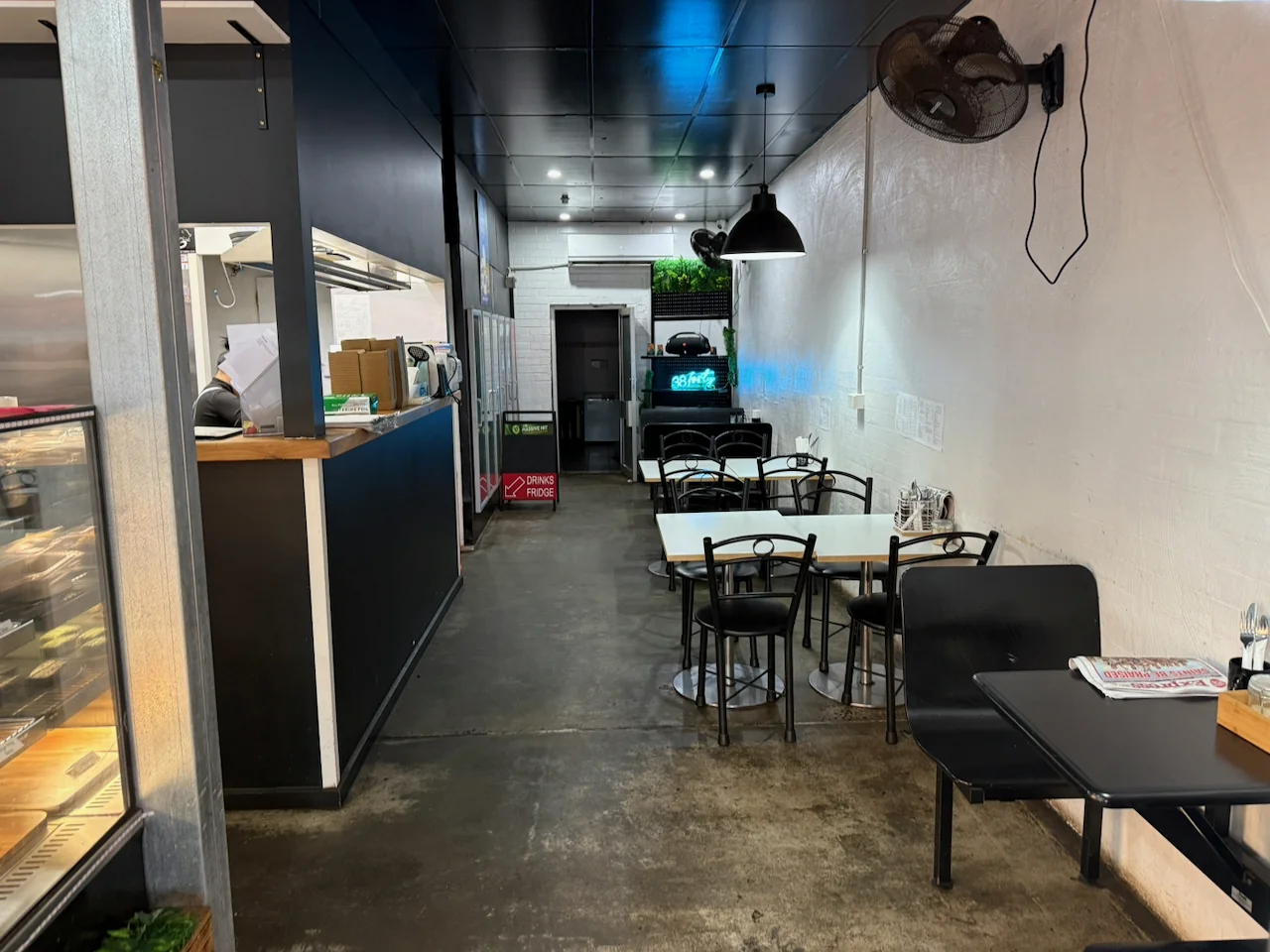 Tables and chairs inside 38Forty Cafe, with the blue cafe sign at the rear