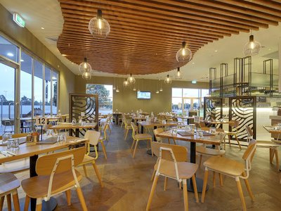Tables set inside Cafe Qu Bah beneath timber ceiling slats and pendant lights.