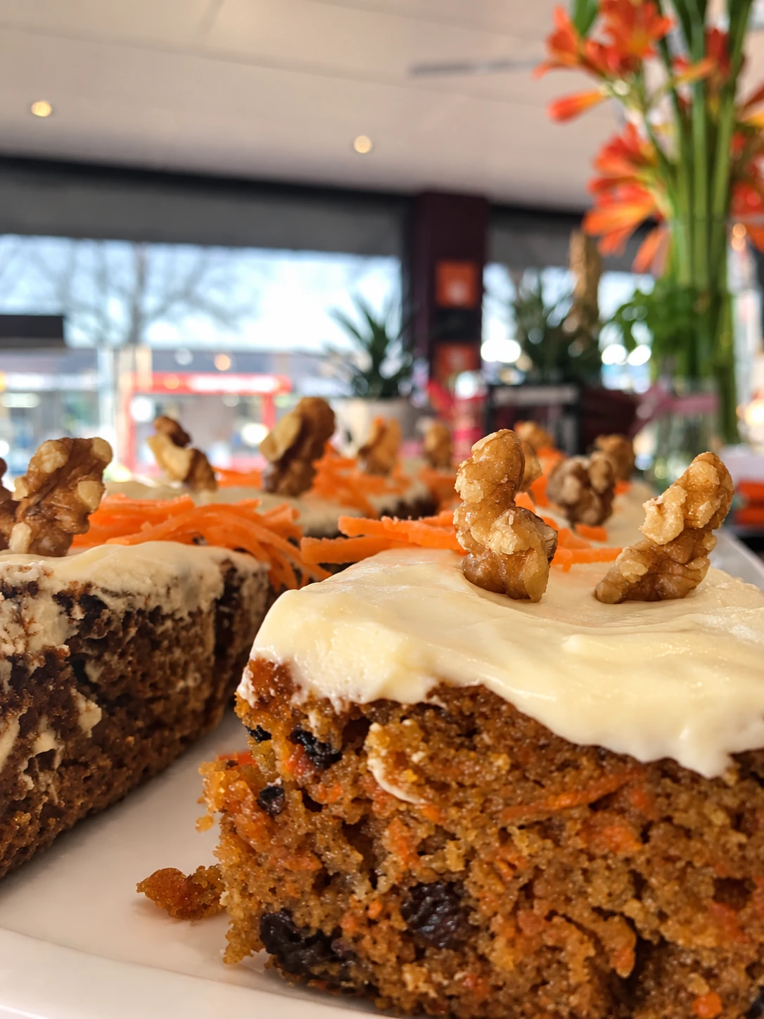 Slices of iced carrot cake topped with walnuts