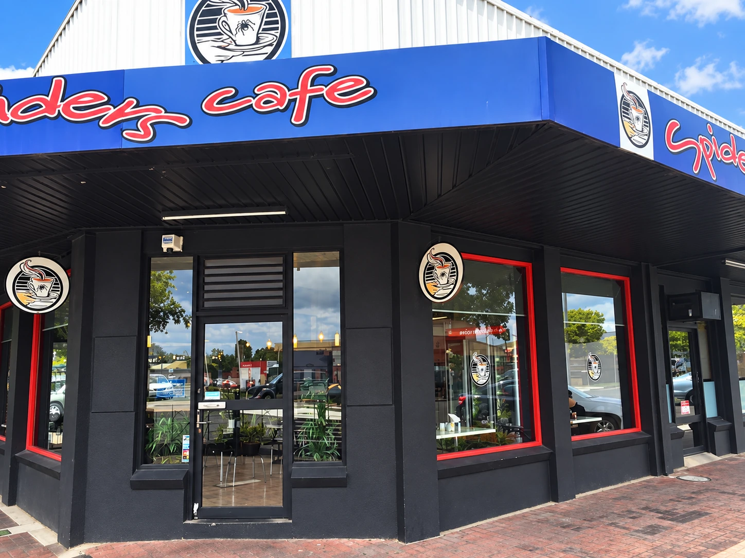 Black corner storefront of Spiders Cafe with blue signage and red-trimmed windows in Moe