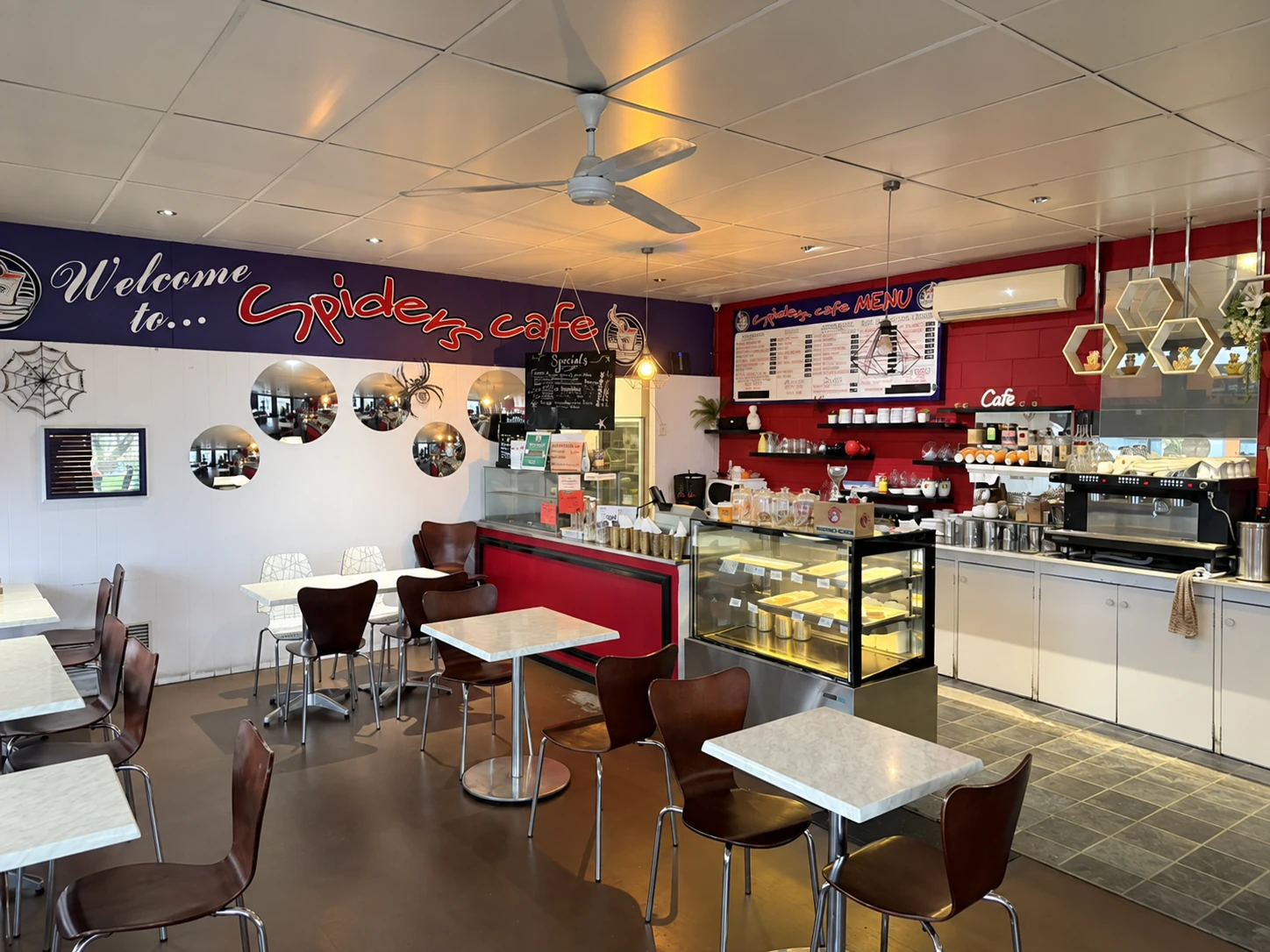 Tables, chairs, counter and food display inside Spiders Cafe in Moe