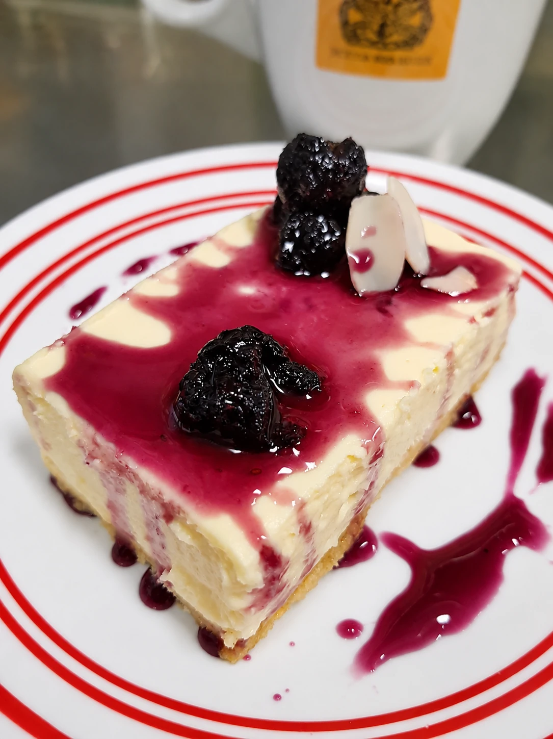 Cheesecake slice with glossy red berry topping and dark berries on a red-rimmed plate