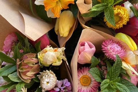 Close view of colourful seasonal bouquets wrapped in brown paper.
