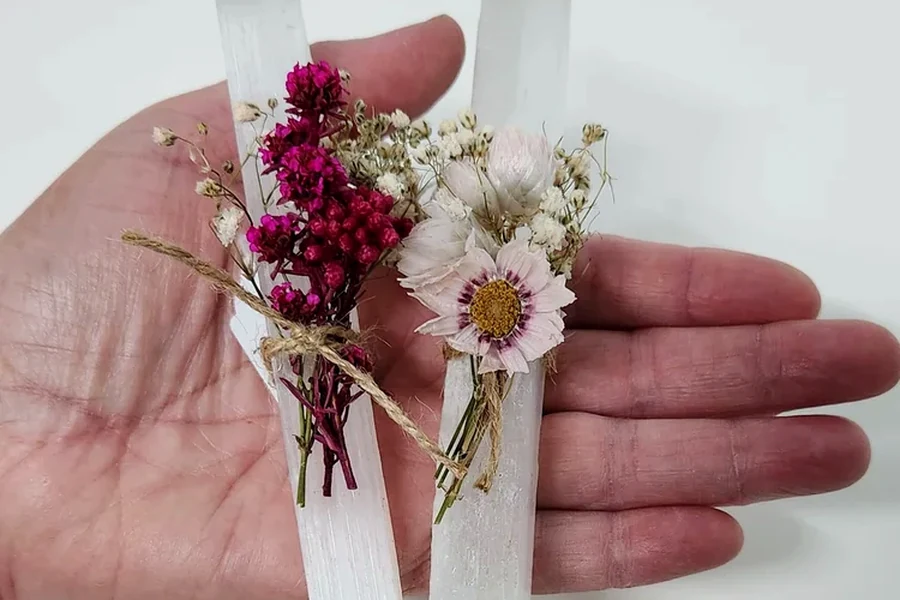 Two white decorative crystal points finished with dried flowers and ribbon.