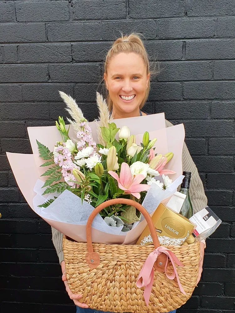 A Lilly Pilly team member smiling above flowers and a woven gift basket.