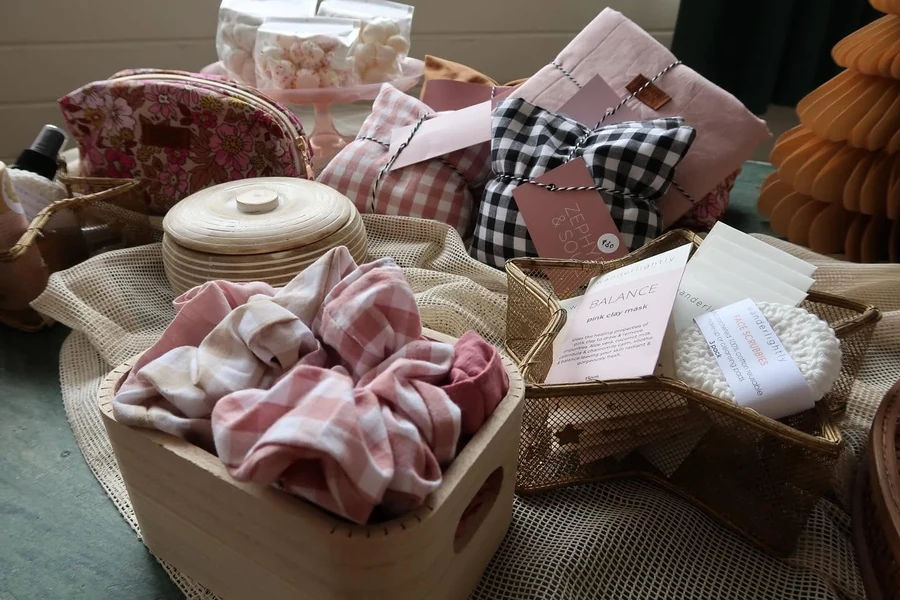 Pink gingham fabric gifts, toiletry bags, soaps and small homewares arranged on a table.