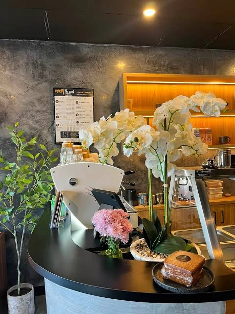 White orchids, coffee equipment and a cake on The Grand Ceylon counter.