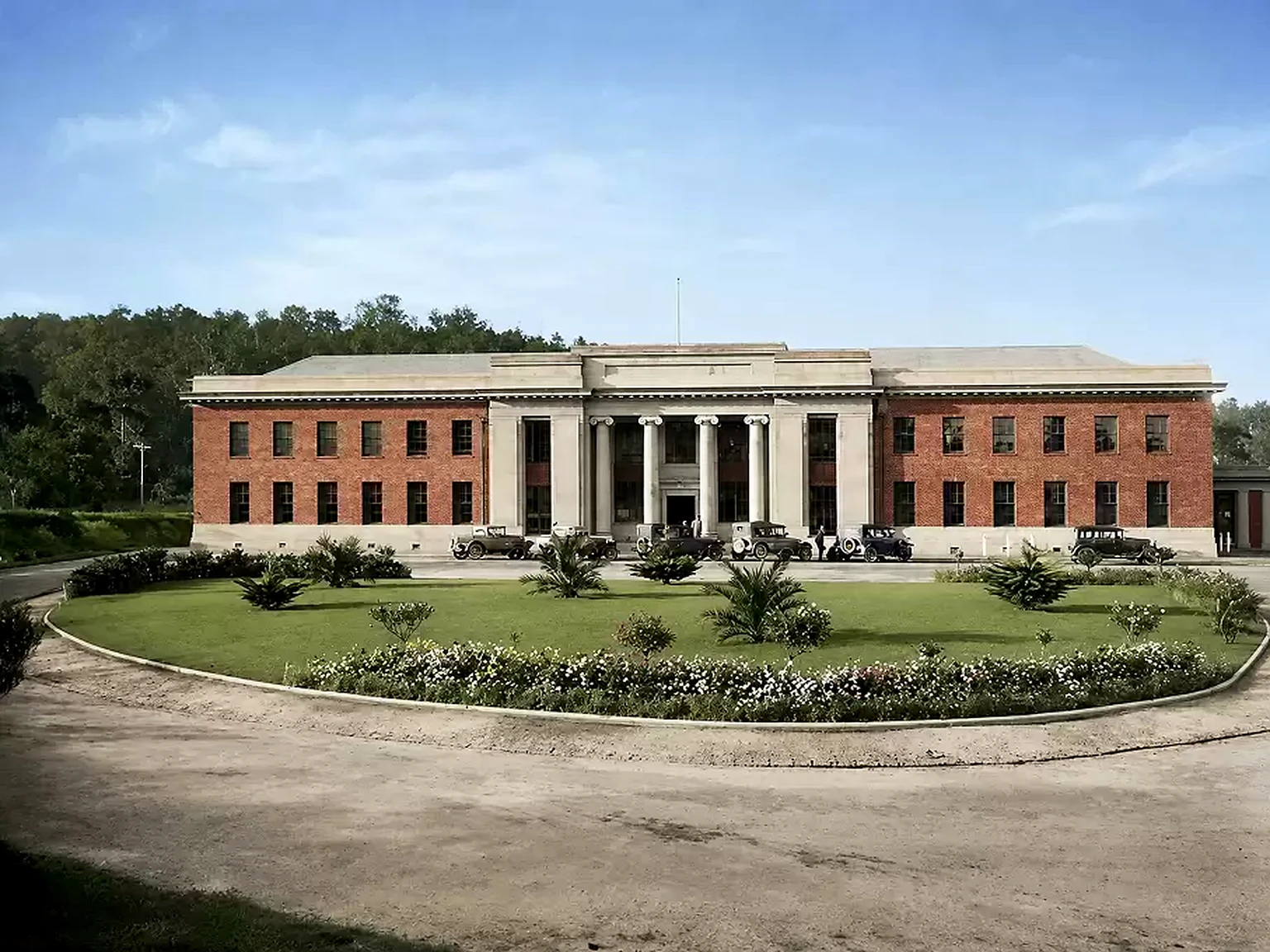 Historical view of the Yallourn administrative building, formal garden and parked cars.