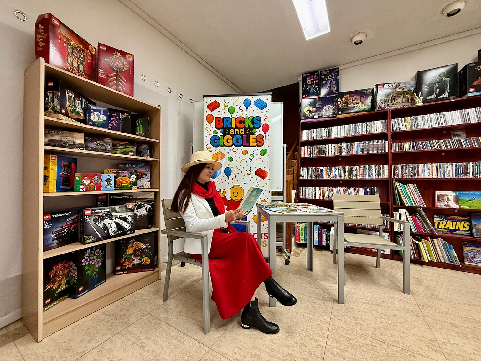 Visitor reading in a room furnished with books, armchairs and Bricks and Giggles displays.