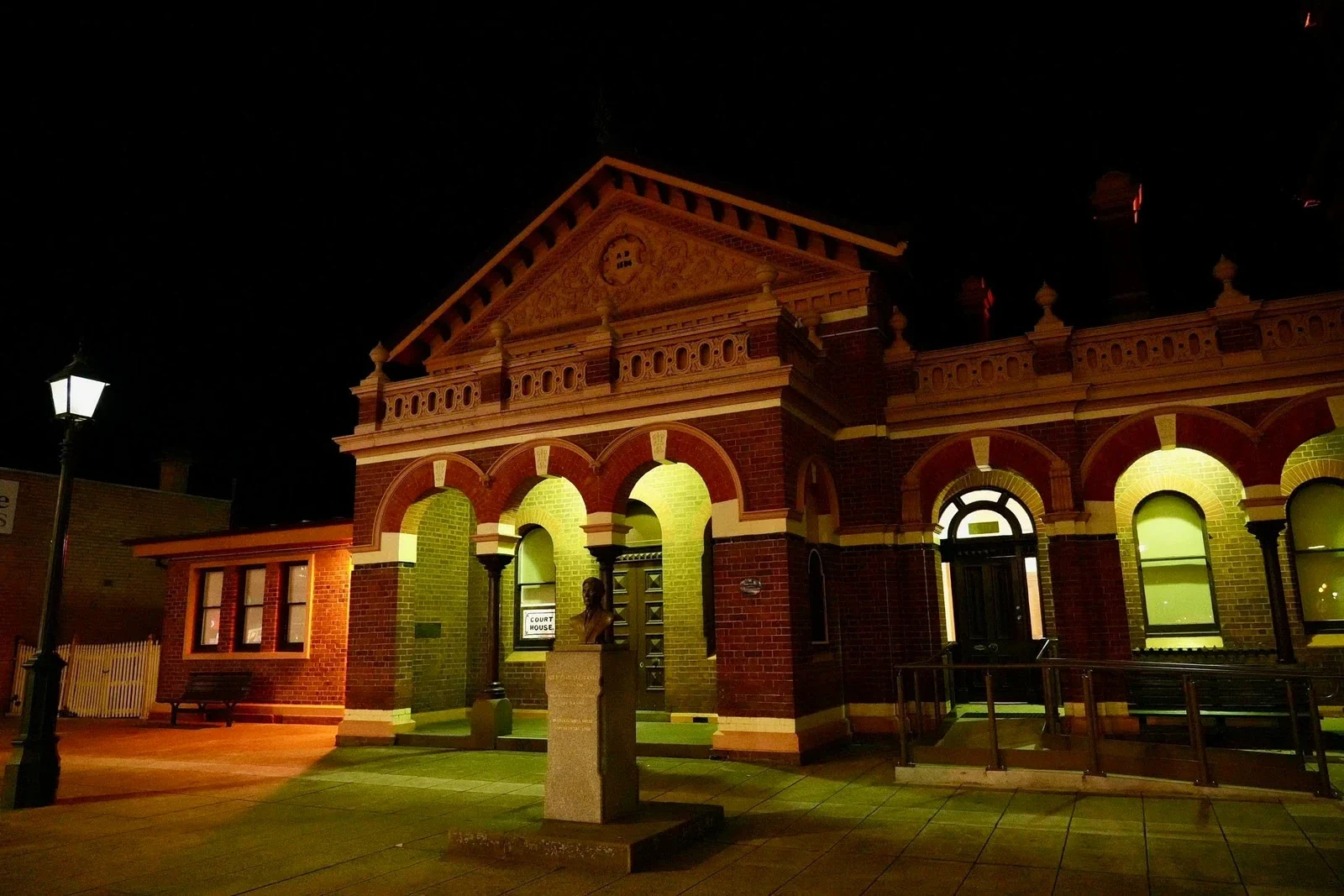 Warm light picks out the brick arches and entrance of Traralgon Courthouse at night.