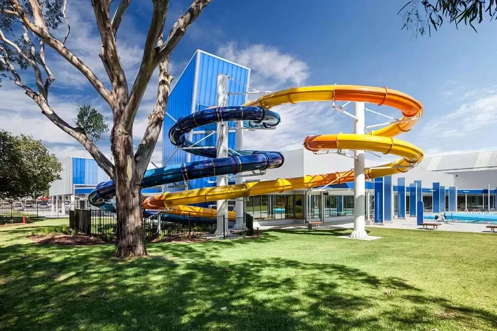 Blue, orange and yellow waterslides curve around the Gippsland Regional Aquatic Centre exterior.