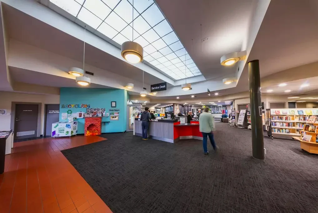 Visitors approach the service desk beneath a large skylight inside Traralgon Library.