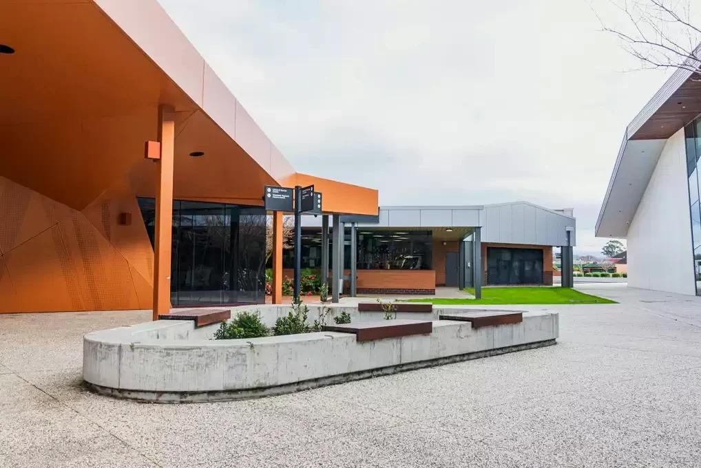 Concrete planters and low seats shape a courtyard beside Traralgon Library's copper-coloured walls.