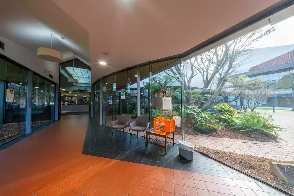 Curved glass brings garden views and daylight into the approach to Traralgon Library's service desk.