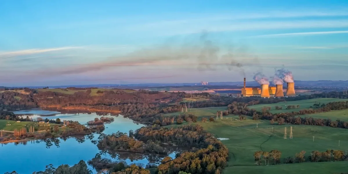 Wide view across farmland and water towards Yallourn Power Station and its cooling towers.