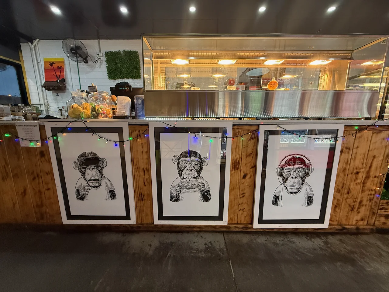 The hot-food counter with three framed monkey illustrations below it