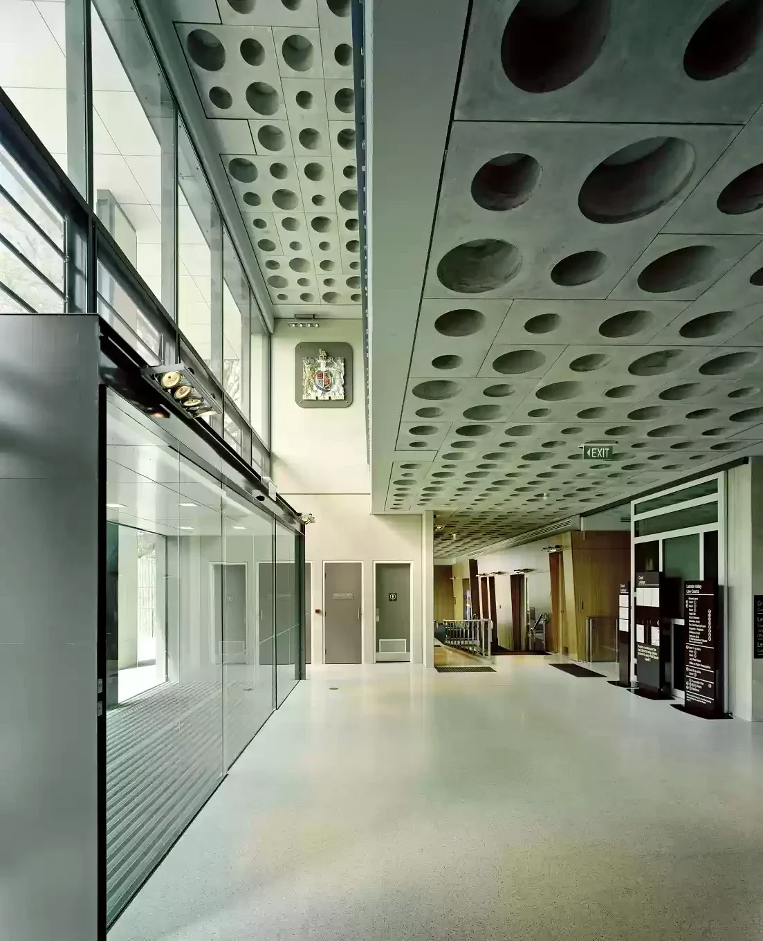 An empty law-courts foyer beneath a ceiling patterned with circular openings.