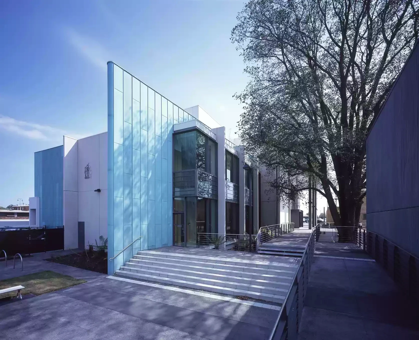 Steps and ramped paths lead between trees and glass façades at the law courts.